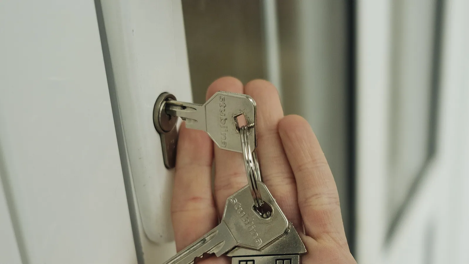 A hand holding house keys at a front door